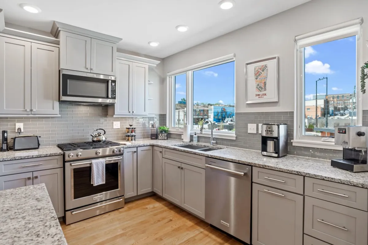 A bright, inviting kitchen featuring sleek granite countertops, stainless steel appliances, and expansive windows that bathe the space in natural light. The open layout creates an ideal spot for preparing group meals or gathering before heading out for an evening downtown.