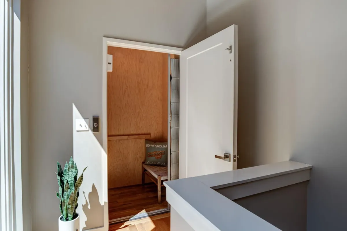 A cozy, light-filled nook by an open door with a potted plant and a wooden floor, suggesting an inviting point of entry or exit. The scene evokes the ease of stepping out to explore or returning home to a welcoming, peaceful retreat.